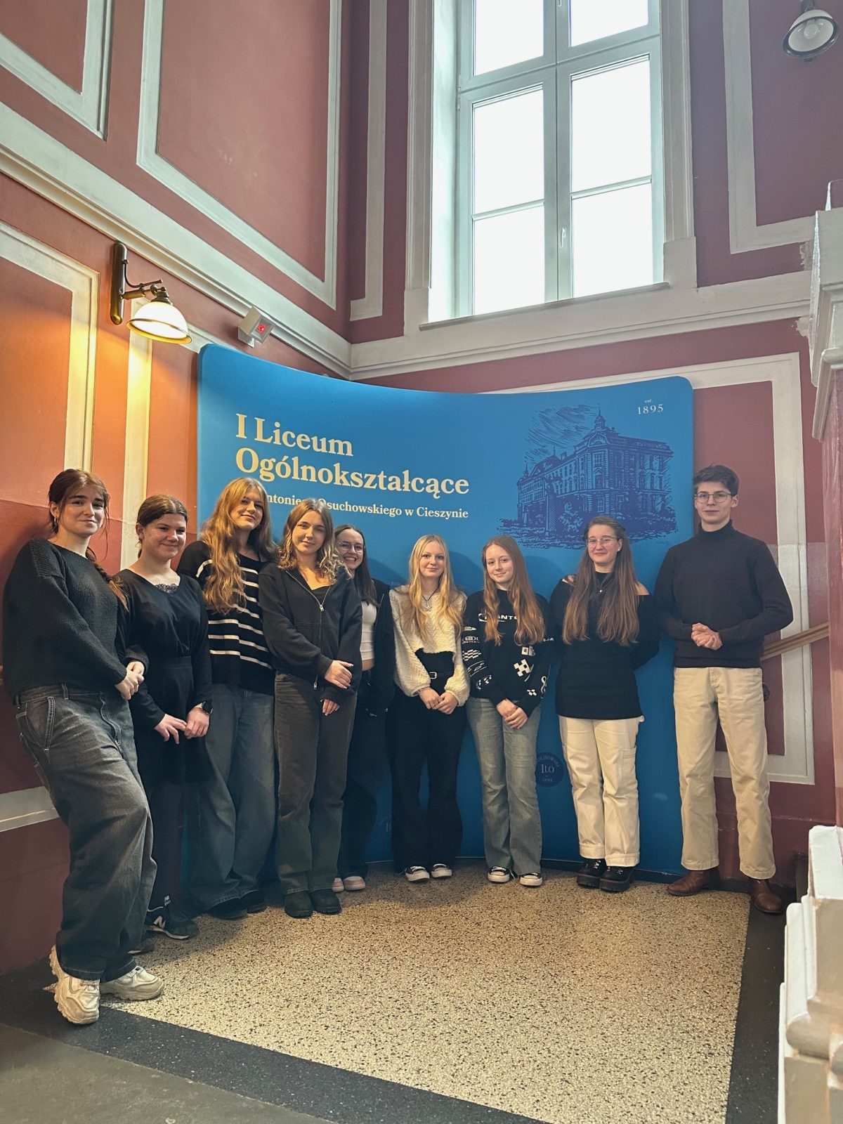 osoby stojące przy ściance szkoły