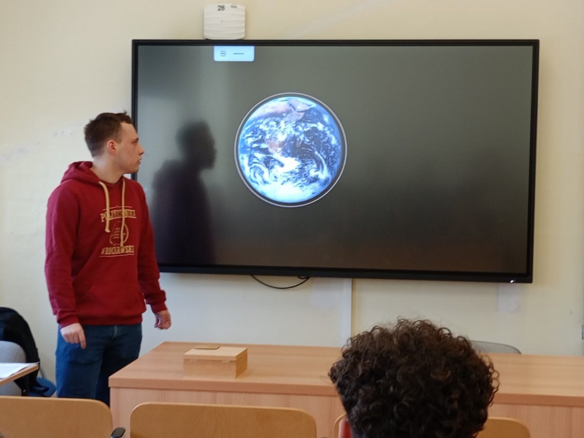 osoba stoi przy tablicy i ma prelekcję